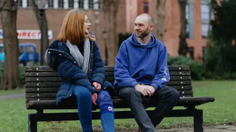 Comic Relief Tara and James sat on a bench talking.