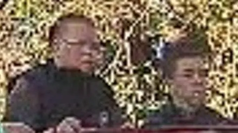 Avon and Somerset Police Two men standing by each other in a blurry CCTV image. One is wearing a black gilet and glasses and the other has short dark hair and is wearing a dark top