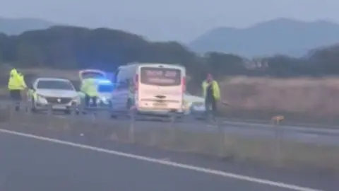 Police vehicles and officers in high-vis sutrrounding a grey van with taxi branding.