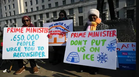 Getty Images Supporters and members of Age UK deliver a petition with over 650,000 signatures to Downing Street - they are holding signs saying things like Prime Minister, 650,000 people urge you to reconsider