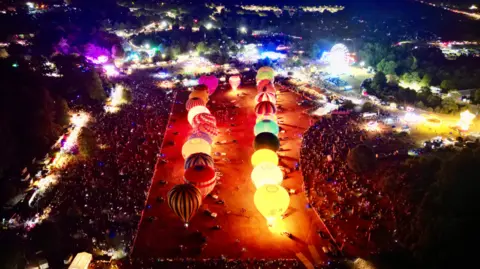 A view over the balloon fiesta with balloons being lit up.