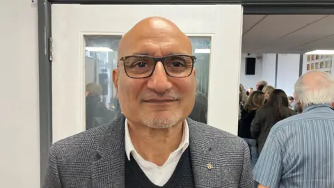 Resident and businessman Nitin Sodha stands in front of the entrance to the public inquiry at Redditch's Woodrow Centre. 