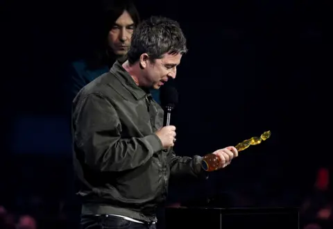 PA Media Noel Gallagher dressed in black looks at his award.