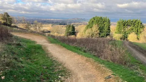 Site of the FlyUp 417 cycle park in Gloucestershire. A dirt track can be seen across the fields, and trees are scattered around. 