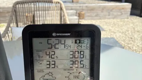 Lainey / BBC Weather Watchers A digital thermometer showing indoor temperature of over 30C, with a garden in the background