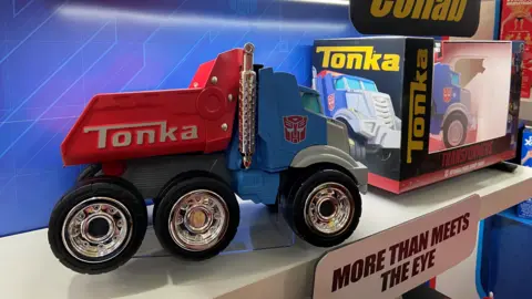 Danielle Kaye/BBC A plastic toy truck sits on a shelf, with the label "Tonka".