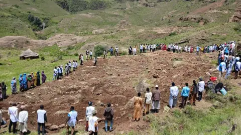 Sudan Liberation Movement/Army People gathering around what looks like a burial site