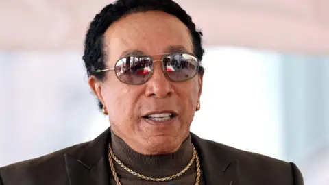 Smokey Robinson in a suit and gold necklaces