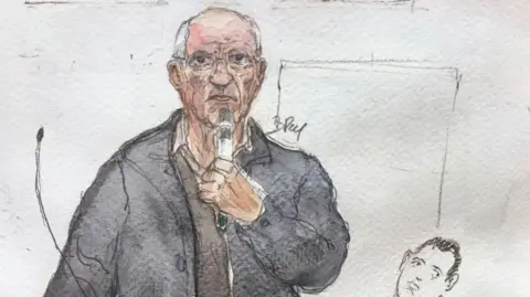 Benoit PEYRUCQ/AFP A court sketch shows the defendant standing with a grey jacket and holding a microphone