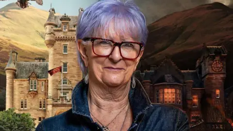 Linda, a 70-year-old woman. She has short purple hair cut in a long fringe over her forehead. She is wearing dark red framed glasses, long silver earrings and a denim top with its collar pulled up and is smiling. Behind her are hills rising to the sky and a stone Scottish baronial-style castle with creamy stone, a grey slate roof and turrets