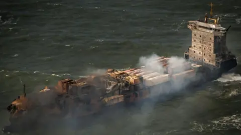 Dan Kitwood/Pool/EPA-EFE/REX/ShuttersTock Smoke undulating from the Solong load ship damaged by fire