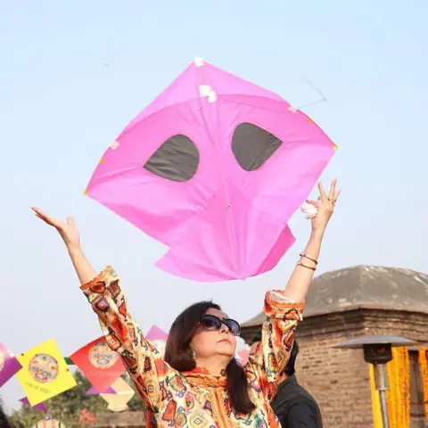 Anadolu/Getty Images A woman holds a kite above her head during the Basant kite festival in Lahore, Pakistan.
