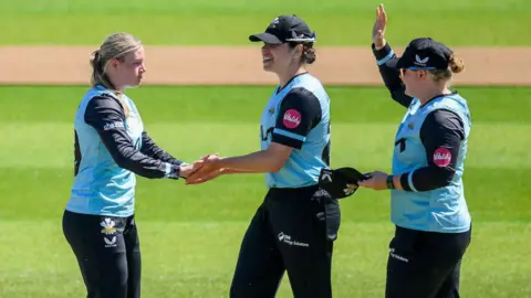 Surrey's Ryana MacDonald-Gay (left) celebrates a wicket with teammates