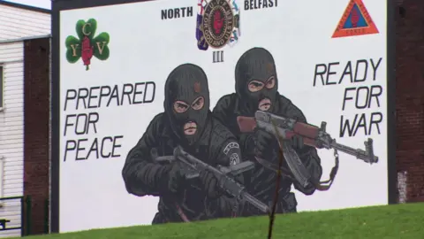 A loyalist paramilitary mural on a gable wall in the Mount Vernon area of north Belfast, showing two masked gunmen alongside text which reads, "Prepared for peace, ready for war".