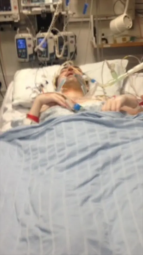 A man lying in a hospital bed attached to tubes.