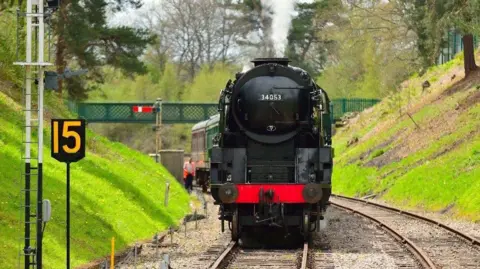 A black and red heritage train travelling on the line. 