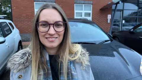 Vicky Beaumont standing in front of her car
