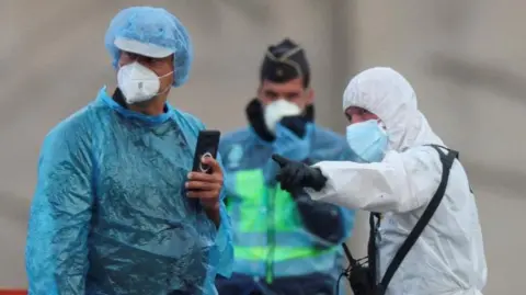 Medical workers in PPE speak to eachother while wearing facemasks and suits