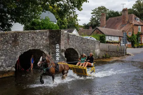 Dan Kitwood / Getty Images A horse and cart ride through the ford on the River Darent