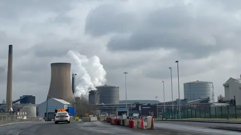 PA Media British Steel in Scunthorpe, with cooling towers and production facilities in view, as well as an entrance gate.