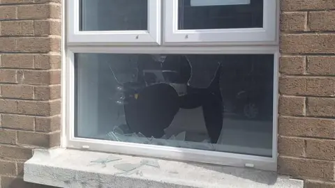 A close up of a broken window - showing shards of glass on a window sill