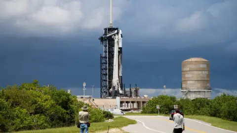 Un cohete SpaceX Falcon 9 se prepara para lanzar Polaris Dawn, una misión espacial tripulada privada, mientras los fotógrafos observan desde el Centro Espacial Kennedy en Cabo Cañaveral, Florida, el 26 de agosto de 2024.