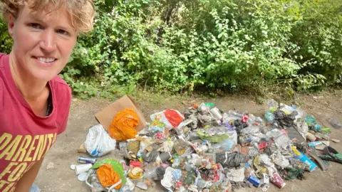 Stroud District Green Party Image of Green councillor Gill Thomas in the foreground and to the left. A pile of miscellaneous items of litter is to the right of the image.