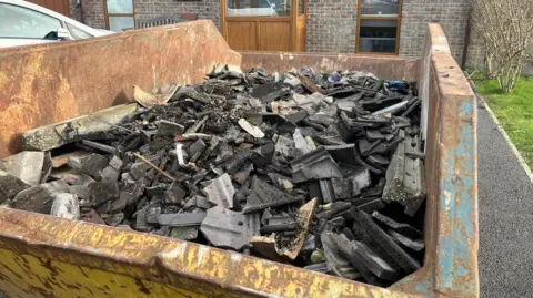 A skip full of debris outside a house