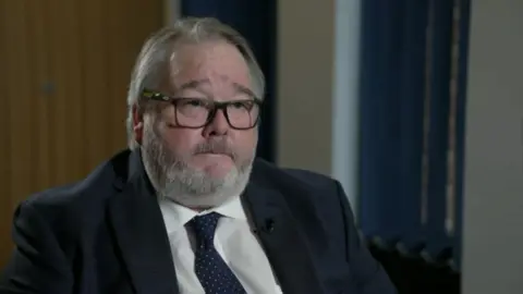 Christopher Mills, in a suit and tie 