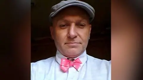 Nottinghamshire Police A headshot of a man in a flat cap and pink dicky bow issued by police