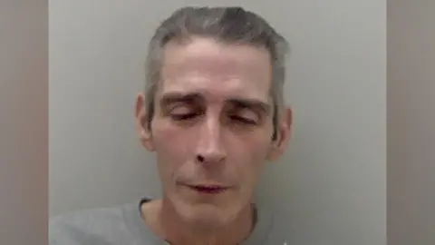 Mark Jesse with his eyes closed in a grainy police mugshot