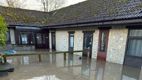 World Horse Welfare The picture shows the exterior of a one-storey building damaged by muddy floodwater.