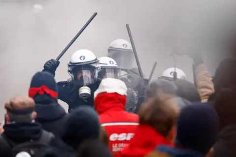 Stephanie Lecocq/Reuters Polisi Riot memegang tongkat mereka saat mereka menghadapi demonstran di Brussels, Belgia