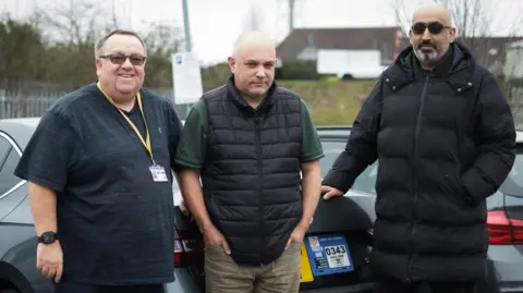 Darren Fitchett, Lee Roach and Manpreet Singh Malhi stood in front of taxi vehicles