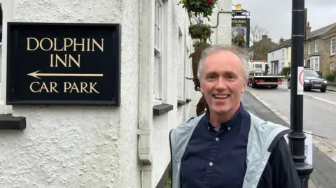 Man standing in front of Dolphin Inn in Grampound - he has grey hair 