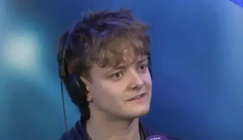 Picture of Matt Hennessy, who has short mousey hair, sat in a studio with headphones on.