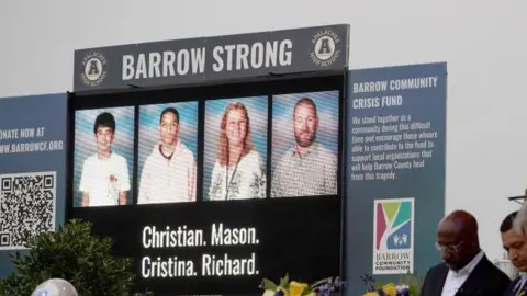 Getty Images A digital screen with images showing Christian Angulo, 14, Mason Schermerhorn, 14, and teachers Richard Aspinwall, 39, and Cristina Irimie, 53.
