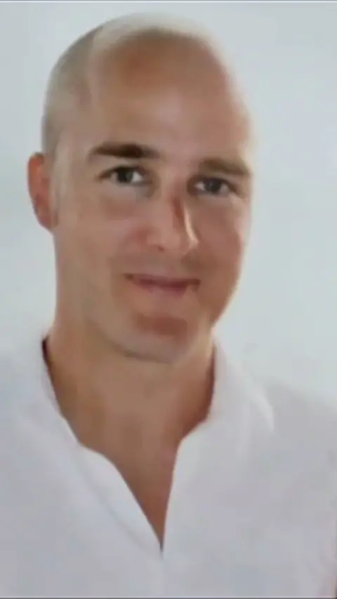Bald man wearing white shirt looking to camera