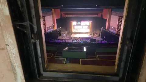 The main auditorium can be seen through a small window.