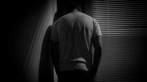 Man standing in the corner of a darkened room