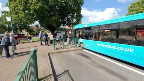 BBC The 64 bus with passengers queuing to get onto the bus