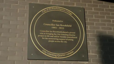 City of Wolverhampton Council A black plaque with gold lettering that reads, dedicated to councillor Ian Brookfield 1965 to 2023 councillor Ian Brookfield played a pivotal role in bringing the city Learning Quarter project to life and will be warmly remembered for his unwavering support of young people across the city.
