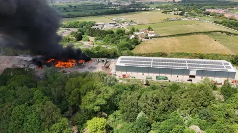 A large fire by an industrial building