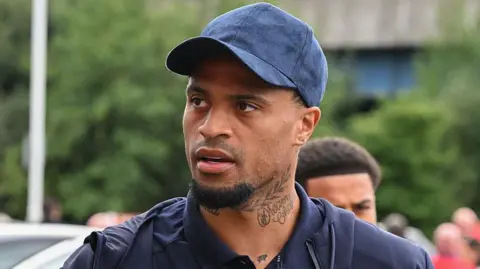Middlesbrough striker Delano Burgzorg dressed in a blue baseball cap and blue polo shirt.
