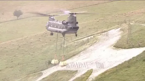 A helicopter hovering above a white horse chalk figure