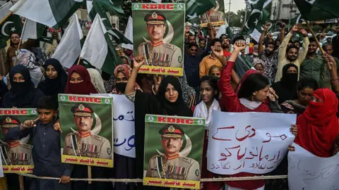 Getty Images Manifestantes seguram bandeiras do Paquistão e cartazes do Marechal de Campo Munir durante um protesto anti-Índia em Karachi em 2 de maio 