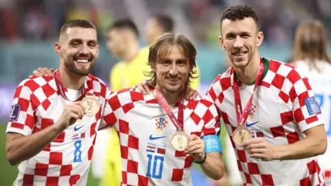 Mateo Kovacic, Luka Modric and Ivan Perisic of Croatia celebrate with their 2022 FIFA World Cup medals 