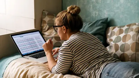 Getty Images Primer plano de una mujer acostada en una cama y escribiendo en una computadora portátil