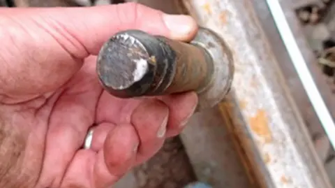 RAIB A hand holding a large screw that appears to be damaged on the end 