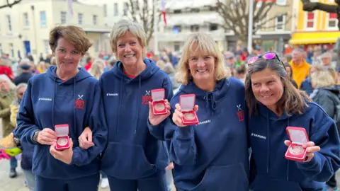 BBC The team holding the medals they received for breaking the world record